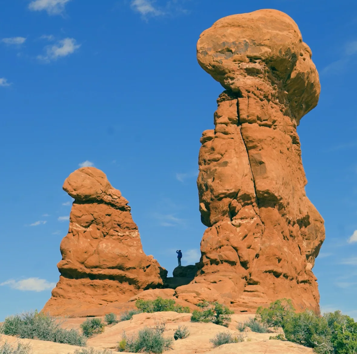 A hiker dwarfed by sandstone towers